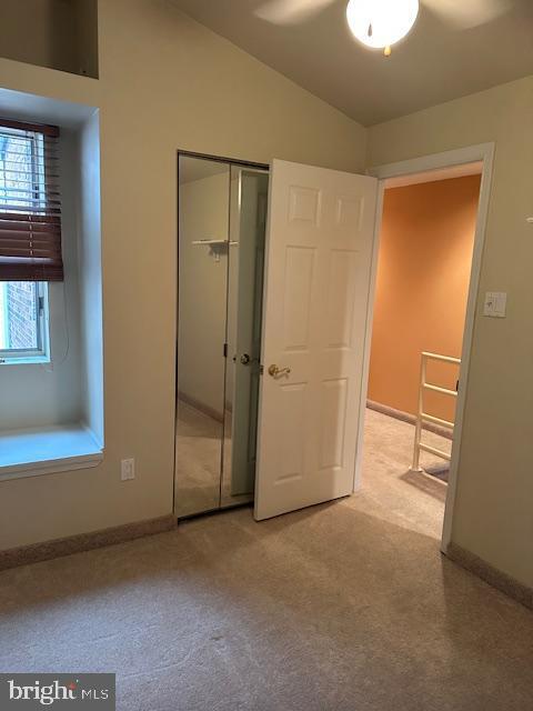 unfurnished bedroom with lofted ceiling, carpet flooring, baseboards, and a closet