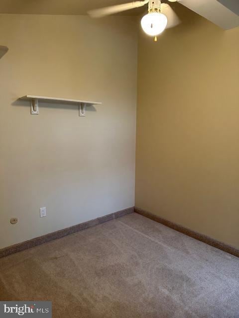 carpeted spare room with a ceiling fan and baseboards