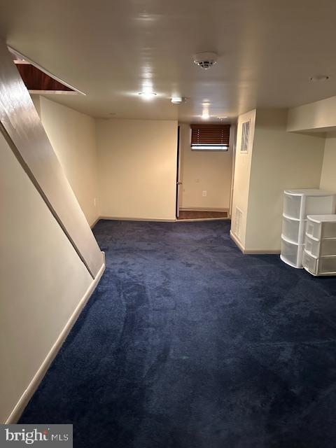 finished basement with dark colored carpet and baseboards