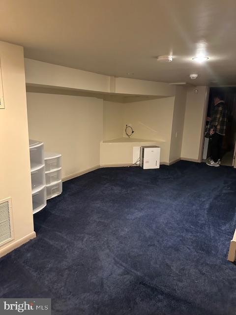 finished basement with visible vents, baseboards, and dark carpet