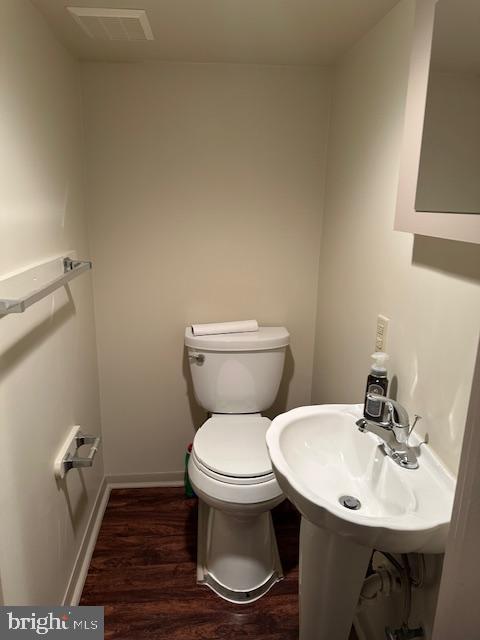 bathroom with toilet, wood finished floors, visible vents, and baseboards