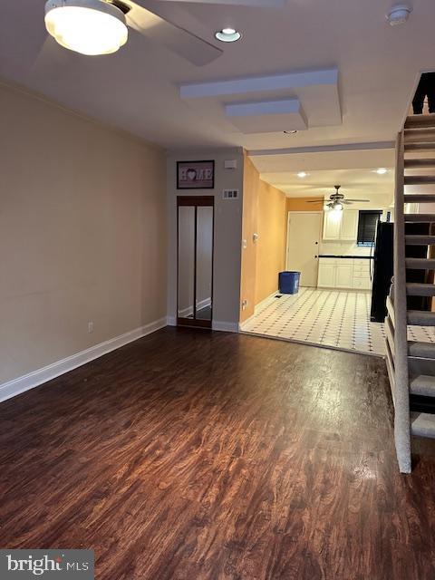 unfurnished living room featuring stairs, wood finished floors, baseboards, and ceiling fan