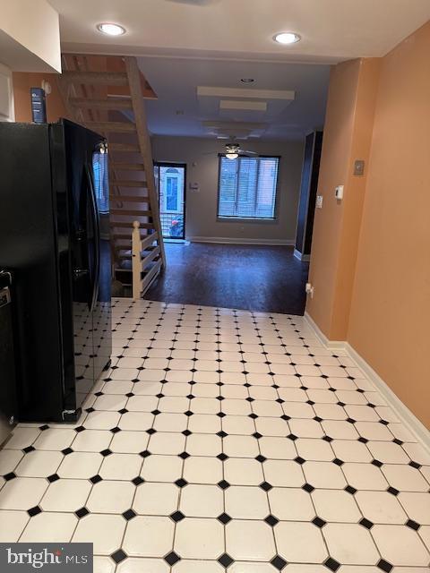 interior space featuring recessed lighting, light floors, baseboards, and black fridge