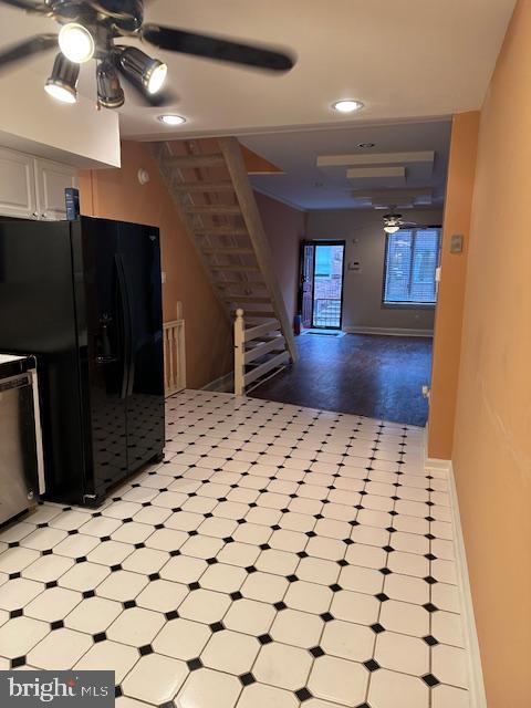 kitchen featuring a ceiling fan, light floors, white cabinetry, freestanding refrigerator, and stove