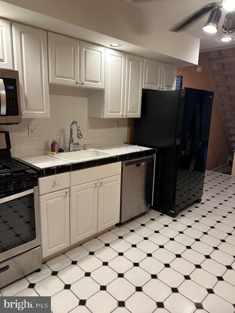 kitchen featuring a sink, appliances with stainless steel finishes, white cabinetry, and tile counters