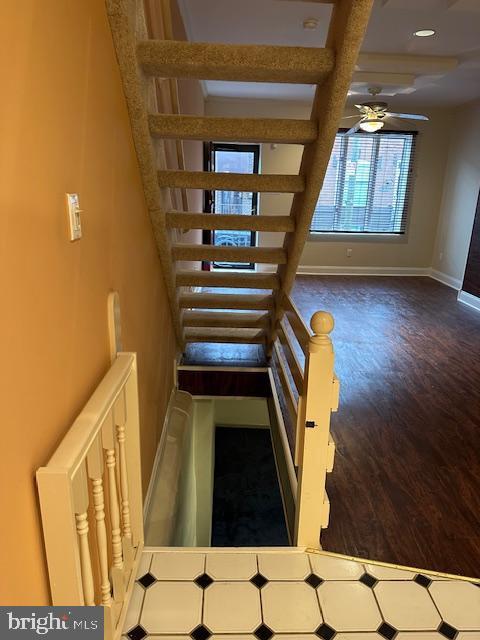 staircase with beam ceiling, wood finished floors, baseboards, and ceiling fan