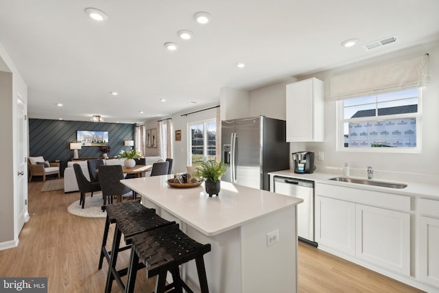 kitchen with visible vents, light wood-type flooring, appliances with stainless steel finishes, white cabinets, and a sink