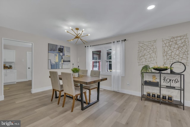 dining space with baseboards, light wood-type flooring, and an inviting chandelier