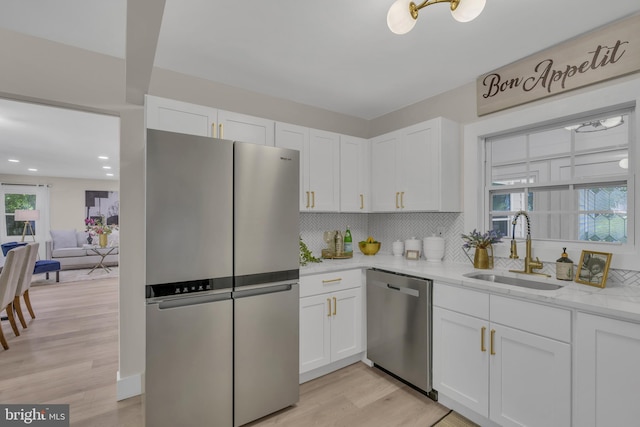 kitchen featuring a sink, white cabinets, light stone counters, and stainless steel appliances