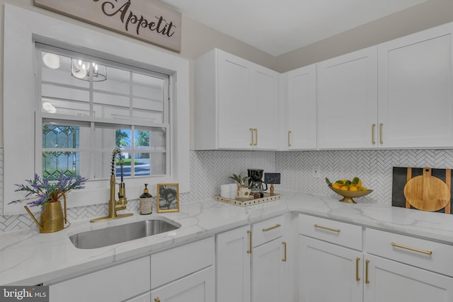 kitchen featuring decorative backsplash, white cabinets, and a sink