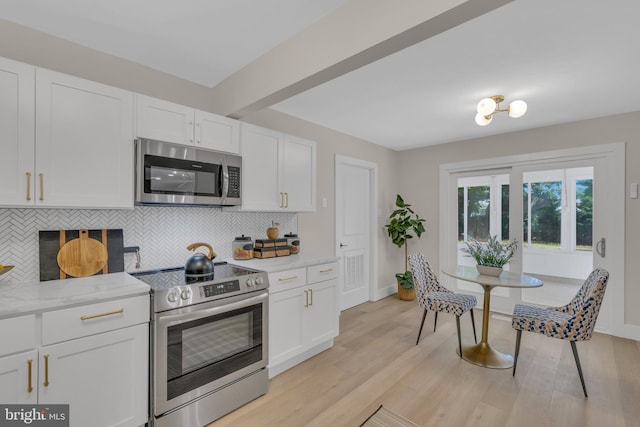 kitchen featuring white cabinets, backsplash, light wood-style floors, and appliances with stainless steel finishes