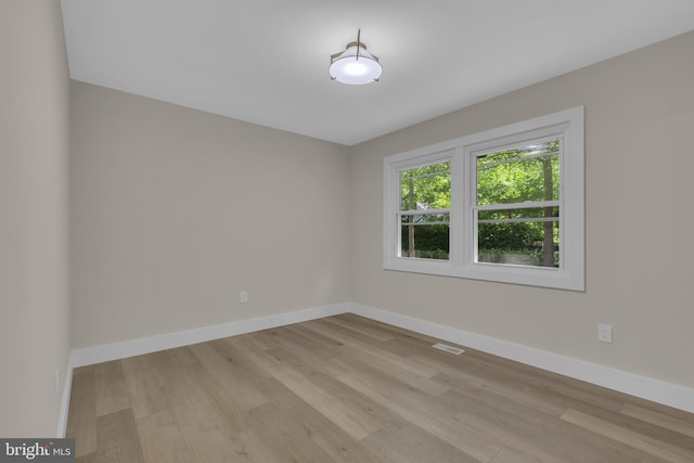 unfurnished room featuring baseboards, visible vents, and light wood finished floors