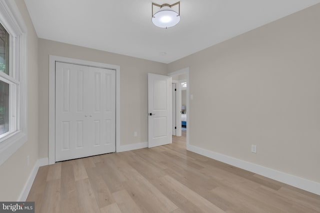 unfurnished bedroom featuring a closet, baseboards, and light wood finished floors