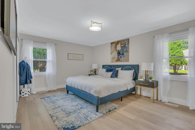 bedroom with visible vents, light wood-style flooring, and baseboards