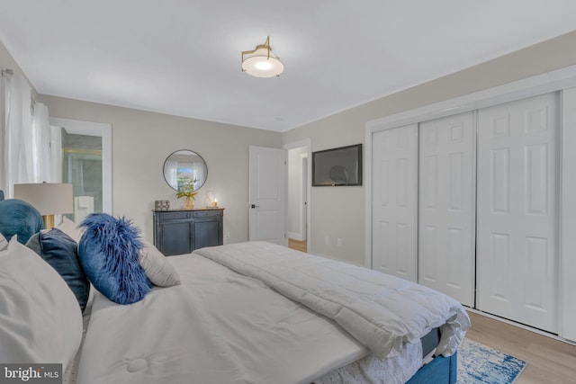 bedroom featuring connected bathroom, a closet, and light wood-style flooring