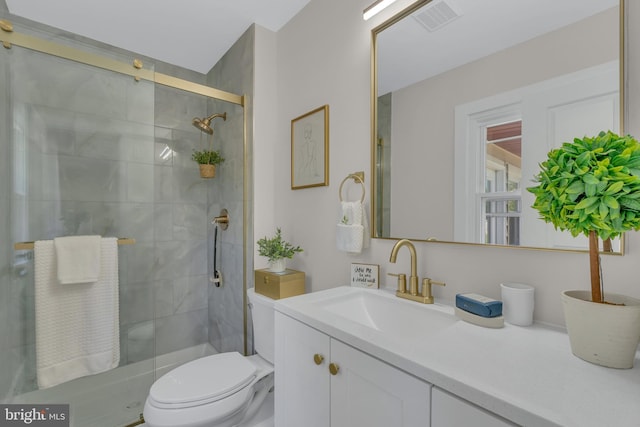 full bath featuring vanity, toilet, visible vents, and tiled shower