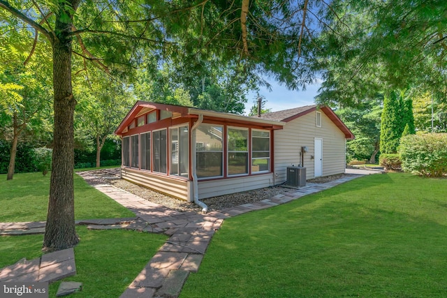 back of property featuring cooling unit, a lawn, and a sunroom