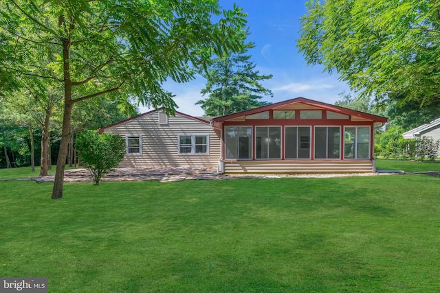 back of property with a lawn and a sunroom