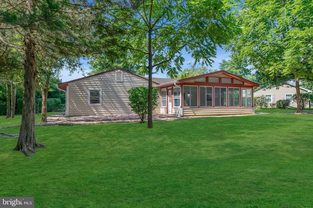 rear view of property with a yard and a sunroom