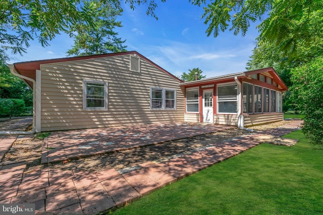 view of front facade featuring a front yard, a patio, and a sunroom