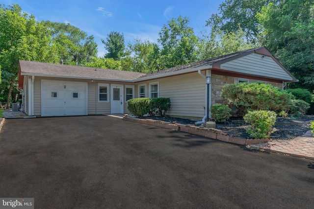 ranch-style house with a garage, stone siding, and aphalt driveway