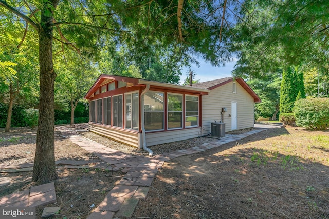 rear view of property featuring central air condition unit and a sunroom