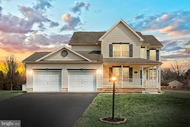 traditional-style house featuring covered porch, driveway, a lawn, and a garage