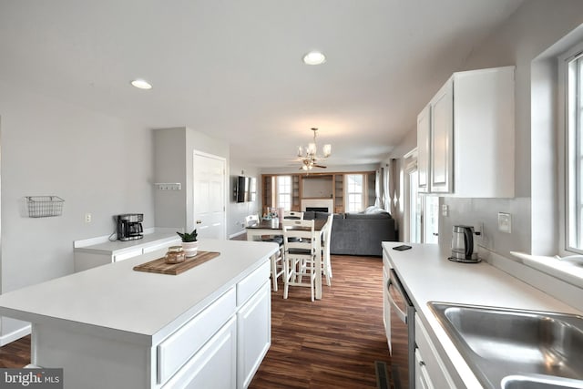 kitchen with dark wood-style floors, a sink, light countertops, white cabinetry, and a chandelier