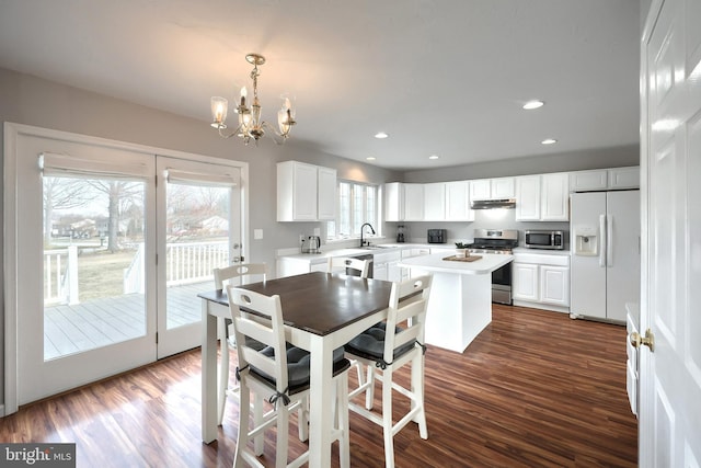 dining area with recessed lighting, dark wood-type flooring, and an inviting chandelier