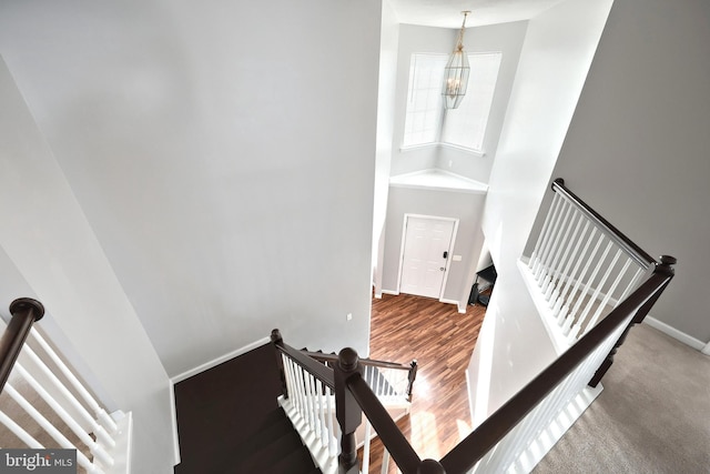 staircase with a notable chandelier, baseboards, and wood finished floors