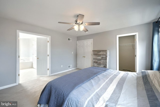 carpeted bedroom featuring ensuite bath, baseboards, visible vents, and ceiling fan