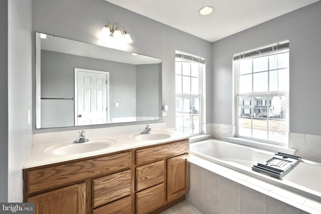 bathroom with double vanity, a bath, and a sink