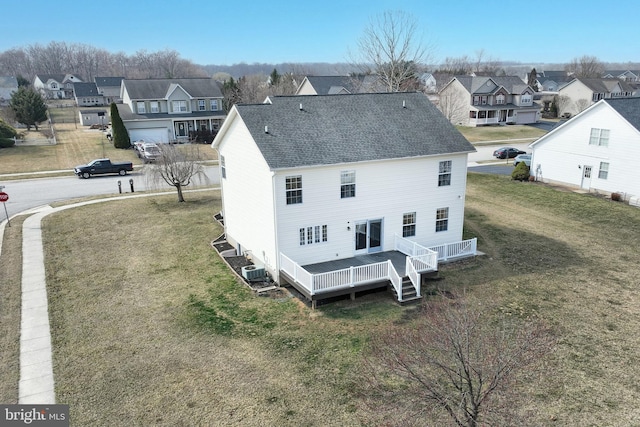 rear view of property featuring a residential view, a lawn, and a shingled roof