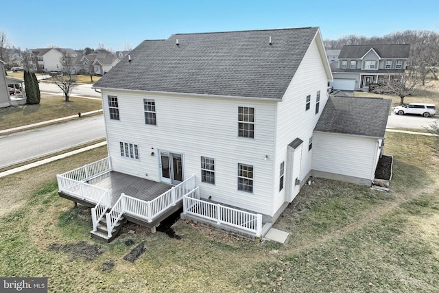 rear view of house featuring a yard, a shingled roof, and a deck