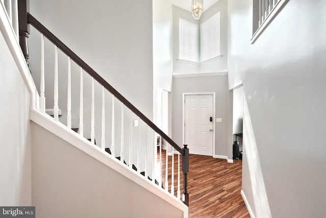 entrance foyer with stairway, wood finished floors, baseboards, and a towering ceiling