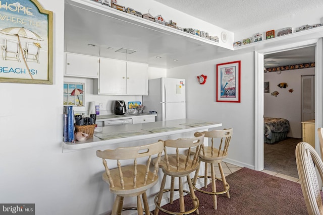 9400 Coastal Hwy Unit 1901, Ocean City, MD 21842 - kitchen with light countertops, light tile patterned floors, a kitchen breakfast bar, freestanding refrigerator, and white cabinetry