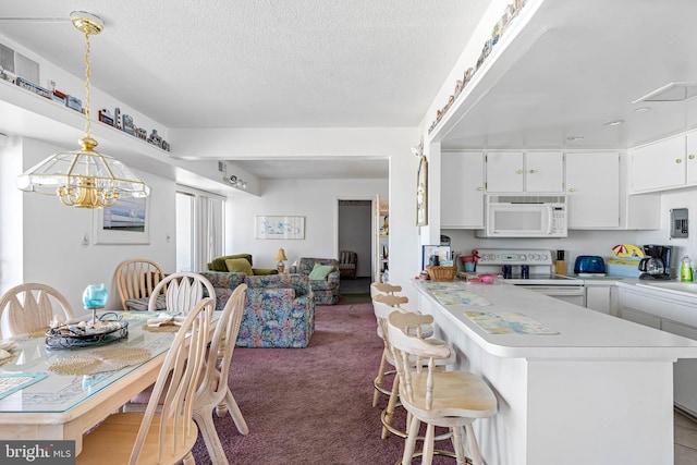 9400 Coastal Hwy Unit 1901, Ocean City, MD 21842 - kitchen featuring white appliances, a peninsula, light countertops, white cabinetry, and a kitchen breakfast bar