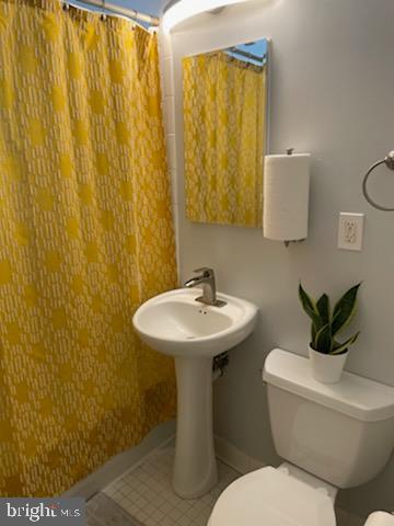 full bath with a shower with curtain, baseboards, toilet, and tile patterned flooring