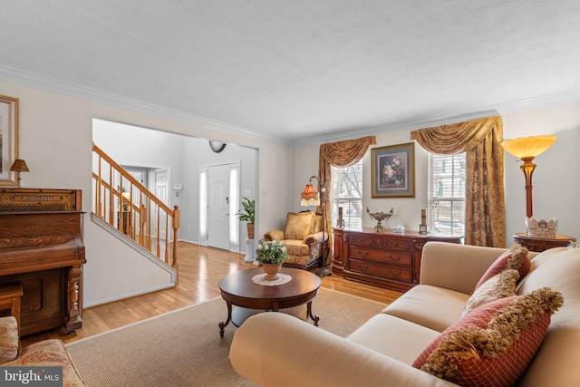 living area with a textured ceiling, stairs, crown molding, and wood finished floors