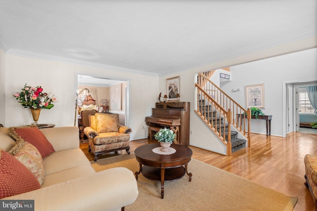 living area featuring stairway, wood finished floors, and crown molding