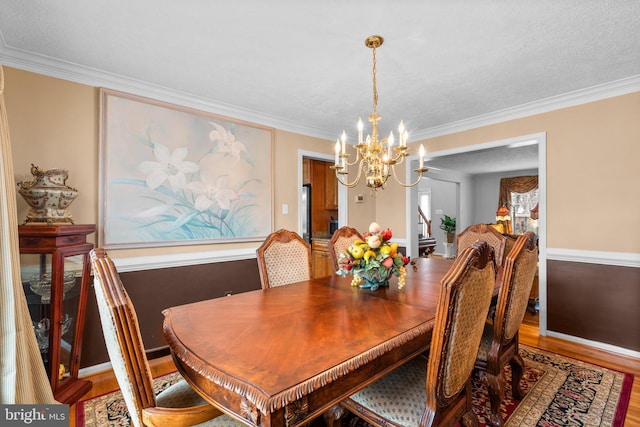 dining space with a chandelier, ornamental molding, and wood finished floors