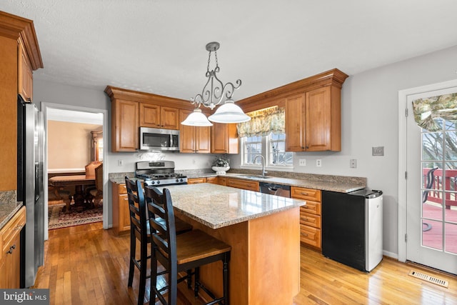 kitchen featuring a sink, visible vents, appliances with stainless steel finishes, and brown cabinetry