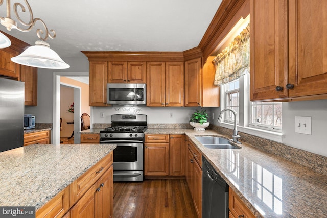 kitchen featuring light stone counters, brown cabinets, appliances with stainless steel finishes, and a sink