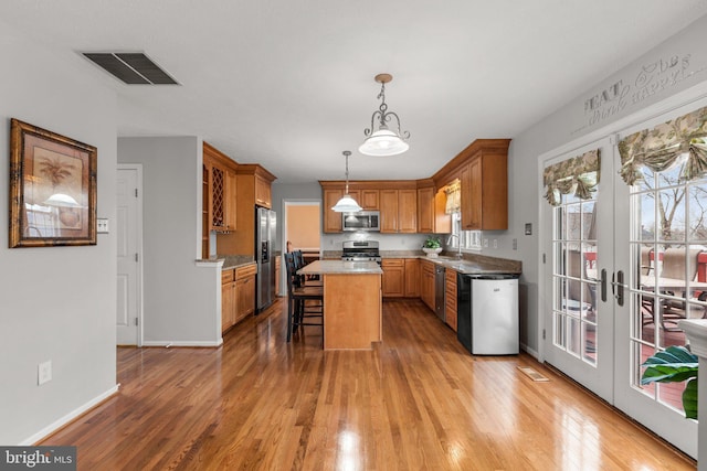 kitchen featuring visible vents, a kitchen bar, a kitchen island, light wood-style floors, and appliances with stainless steel finishes