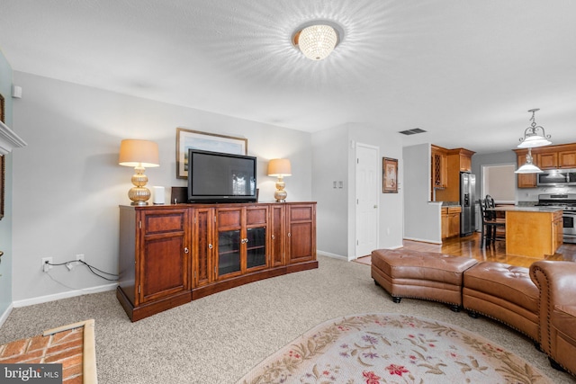 living area with visible vents, baseboards, and light carpet