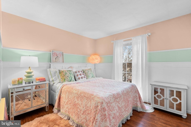 bedroom featuring a wainscoted wall and wood finished floors