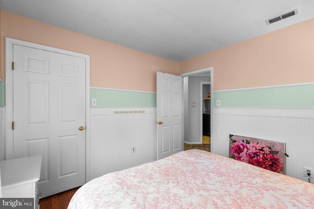 bedroom featuring visible vents, dark wood-style floors, and wainscoting