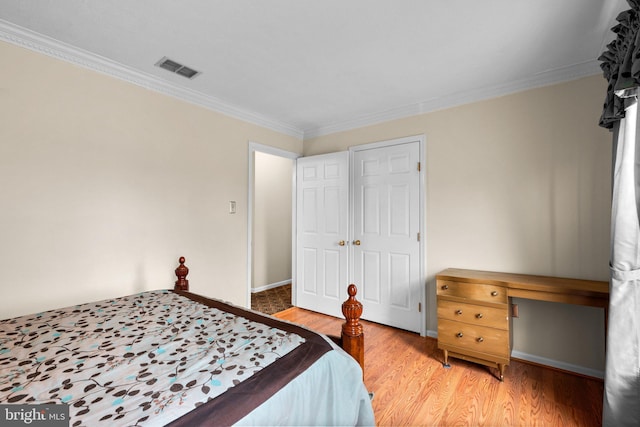 bedroom with visible vents, baseboards, light wood-style flooring, and ornamental molding