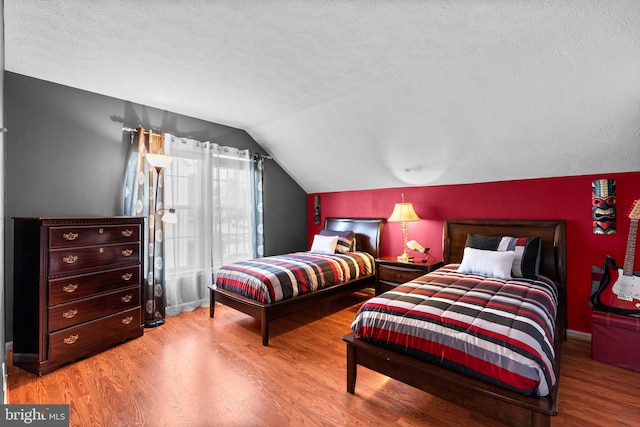 bedroom featuring baseboards, a textured ceiling, wood finished floors, and vaulted ceiling