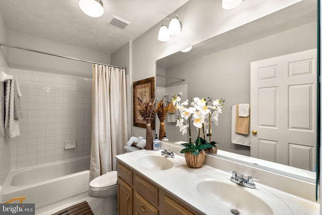 full bath with a textured ceiling, toilet, shower / bath combo with shower curtain, and a sink